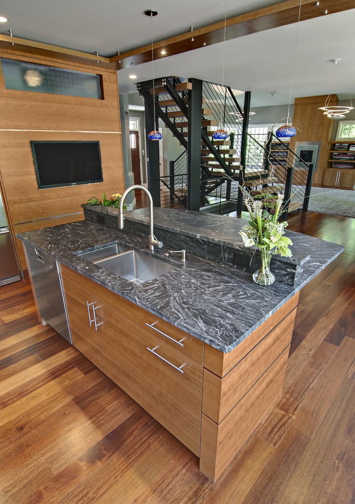 Inspiration for a large contemporary l-shaped open plan kitchen in Minneapolis with an undermount sink, flat-panel cabinets, light wood cabinets, granite benchtops, multi-coloured splashback, glass tile splashback, stainless steel appliances, medium hardwood floors, with island, brown floor and black benchtop.