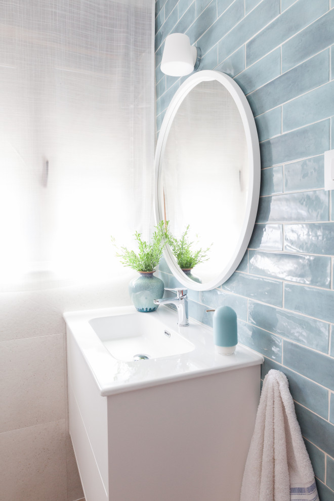 Пример оригинального дизайна: маленькая ванная комната в современном стиле с белыми фасадами, угловым душем, унитазом-моноблоком, синей плиткой, керамической плиткой, белыми стенами, полом из керамогранита, душевой кабиной, накладной раковиной, столешницей из плитки, коричневым полом, душем с раздвижными дверями, белой столешницей, окном, тумбой под одну раковину и подвесной тумбой для на участке и в саду