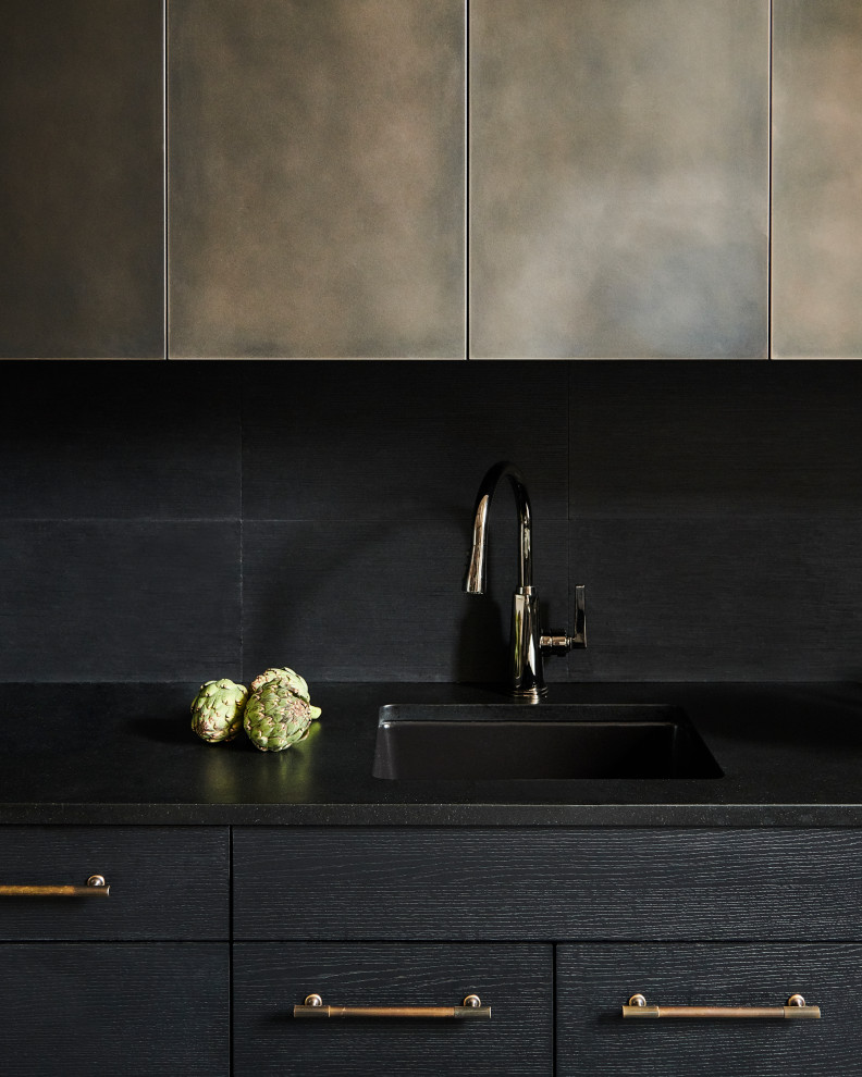 This is an example of a small contemporary l-shaped kitchen/diner in New York with a submerged sink, flat-panel cabinets, black cabinets, granite worktops, black splashback, limestone splashback, integrated appliances, medium hardwood flooring, no island, beige floors and black worktops.