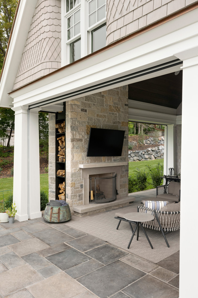 This is an example of a large coastal veranda in Minneapolis with a fireplace, natural stone paving and a roof extension.