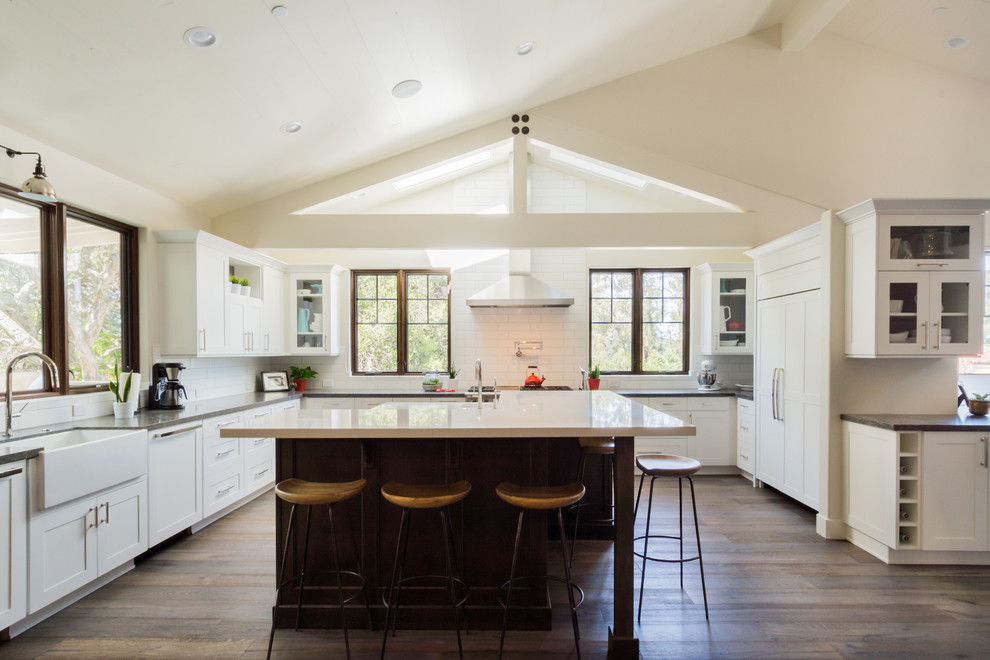 Inspiration for a traditional u-shaped kitchen in San Luis Obispo with shaker cabinets, white cabinets, white splashback, subway tile splashback, panelled appliances, dark hardwood floors, with island and brown floor.
