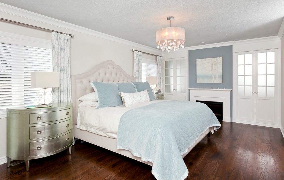 Design ideas for a large transitional master bedroom in Toronto with white walls, medium hardwood floors, a standard fireplace and a wood fireplace surround.