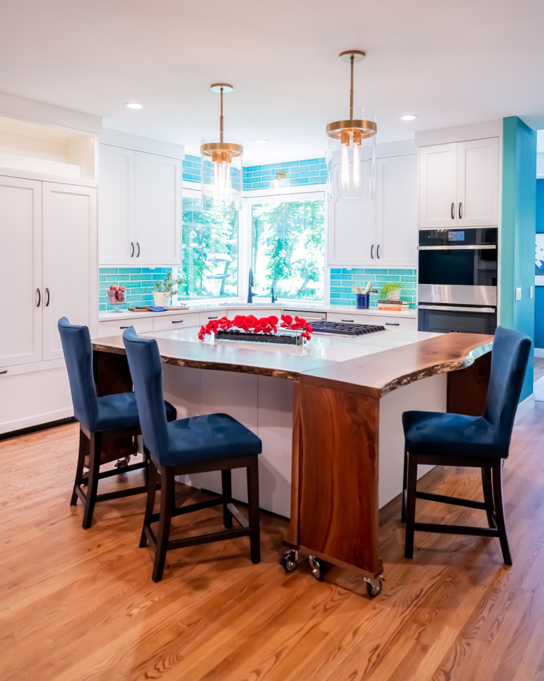 Photo of a modern l-shaped separate kitchen in Cedar Rapids with shaker cabinets, white cabinets, quartz benchtops, blue splashback, subway tile splashback, stainless steel appliances, medium hardwood floors, with island, white benchtop and brown floor.