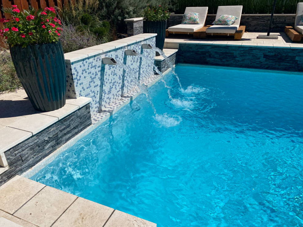 This is an example of a large modern backyard custom-shaped pool in Oklahoma City with natural stone pavers.