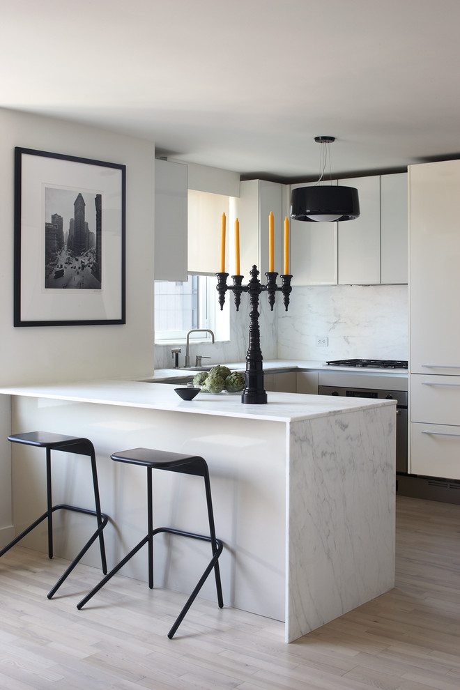 Design ideas for a modern u-shaped eat-in kitchen in New York with flat-panel cabinets, marble benchtops, stainless steel appliances, white splashback and marble splashback.
