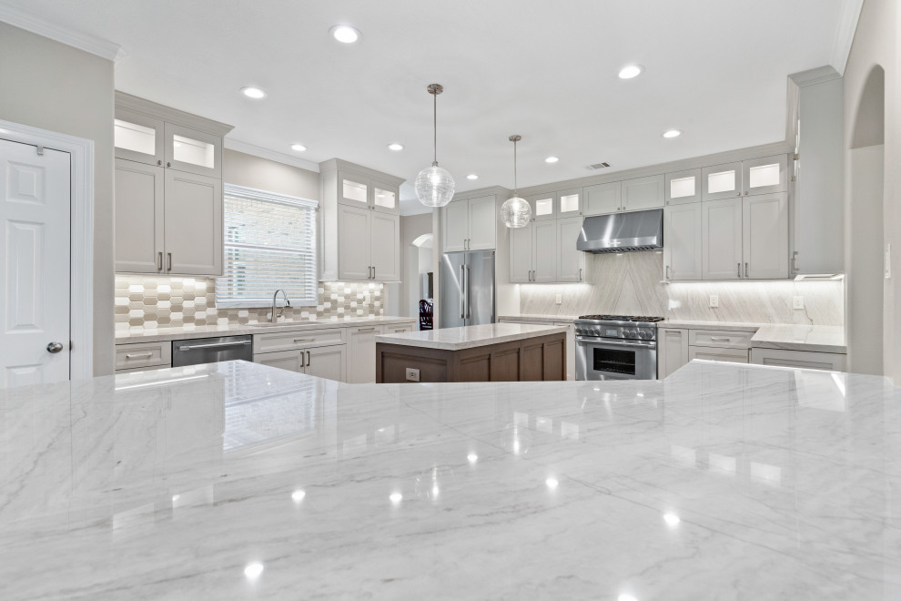 Design ideas for a large transitional l-shaped eat-in kitchen in Houston with an undermount sink, beaded inset cabinets, grey cabinets, quartzite benchtops, grey splashback, ceramic splashback, stainless steel appliances, cement tiles, multiple islands, white floor and grey benchtop.