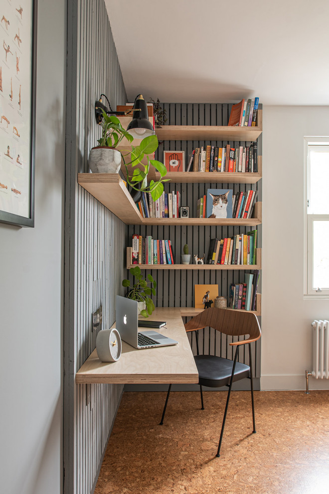 Exempel på ett mellanstort minimalistiskt hemmabibliotek, med grå väggar, korkgolv, ett inbyggt skrivbord och brunt golv