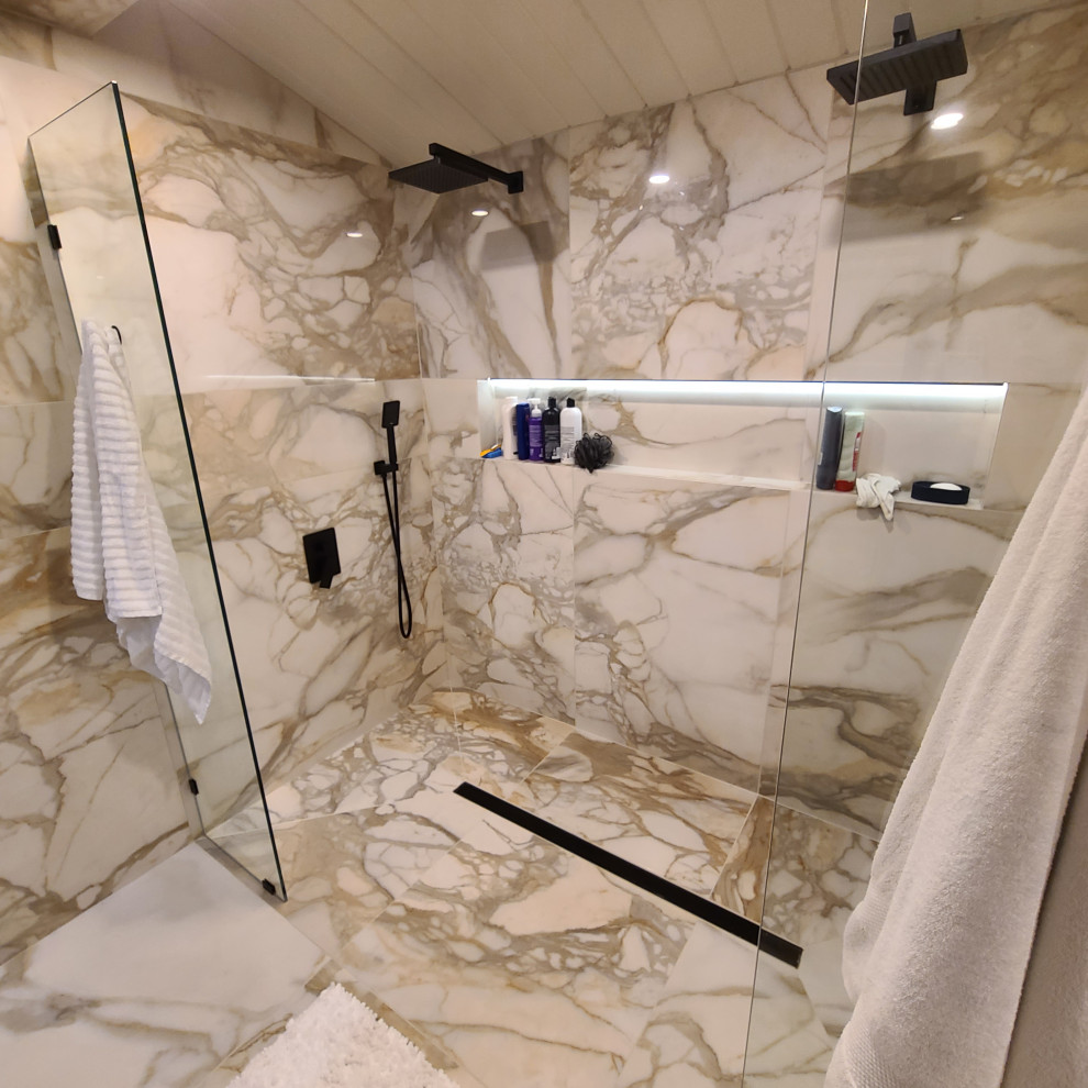 This is an example of a large modern master wet room bathroom in Portland with flat-panel cabinets, medium wood cabinets, a freestanding tub, a wall-mount toilet, white tile, marble, white walls, marble floors, a vessel sink, engineered quartz benchtops, white floor, an open shower, black benchtops, a niche, a double vanity, a floating vanity and vaulted.