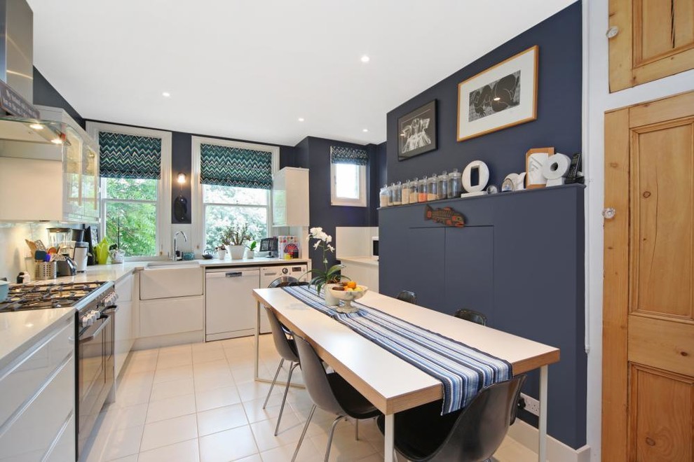 Photo of a mid-sized eclectic l-shaped eat-in kitchen in London with a farmhouse sink, glass-front cabinets, white cabinets, quartz benchtops, white splashback, glass sheet splashback, stainless steel appliances, ceramic floors and no island.