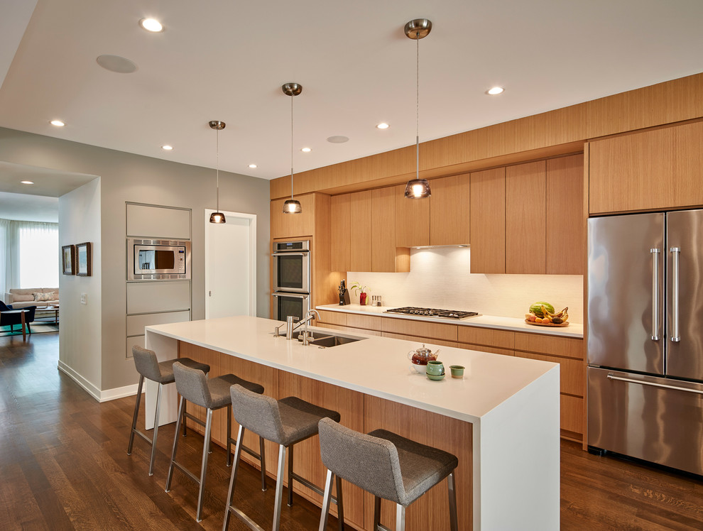Design ideas for a large contemporary kitchen in Chicago with flat-panel cabinets, quartz benchtops, white splashback, stainless steel appliances, with island, brown floor, a double-bowl sink, light wood cabinets and dark hardwood floors.
