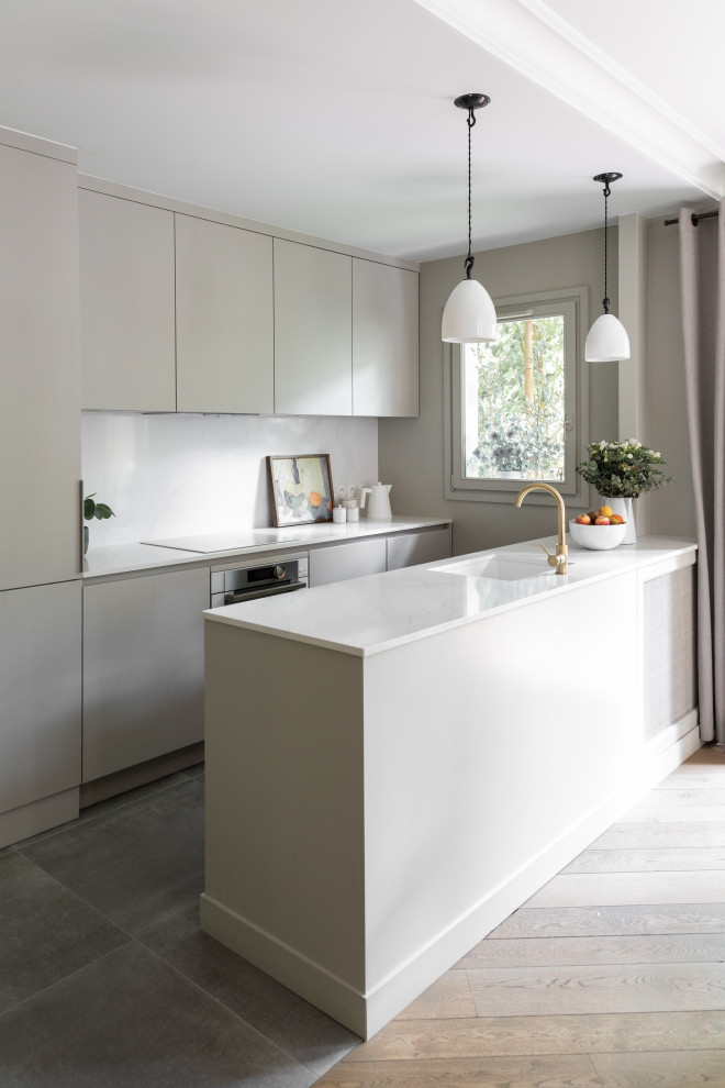 Moderne Küche in grau-weiß mit Unterbauwaschbecken, Küchenrückwand in Weiß, Rückwand aus Quarzwerkstein, Elektrogeräten mit Frontblende und weißer Arbeitsplatte in Paris