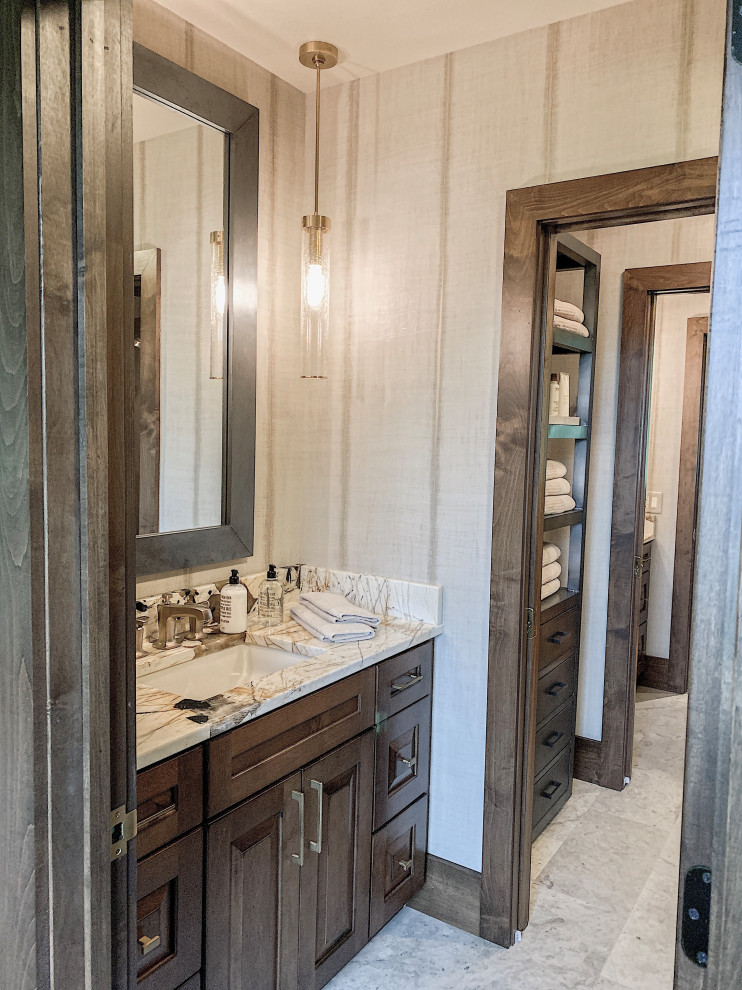 Inspiration for a country bathroom in Charleston with raised-panel cabinets, brown cabinets, an open shower, beige tile, marble, beige walls, marble floors, an undermount sink, quartzite benchtops, grey floor, a hinged shower door, beige benchtops, a single vanity, a built-in vanity and wallpaper.