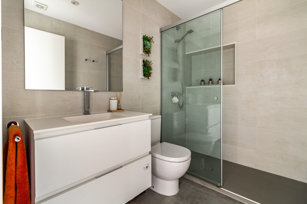 Inspiration för mellanstora moderna vitt badrum med dusch, med vita skåp, en dusch i en alkov, en toalettstol med separat cisternkåpa, beige kakel, keramikplattor, beige väggar, klinkergolv i keramik, ett integrerad handfat, bänkskiva i täljsten, grått golv, dusch med skjutdörr och släta luckor