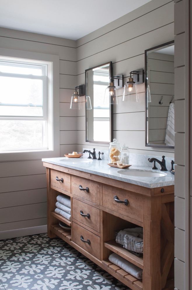 Inspiration for a mid-sized country master bathroom in Burlington with open cabinets, medium wood cabinets, an alcove tub, an alcove shower, a two-piece toilet, gray tile, ceramic tile, grey walls, ceramic floors, an undermount sink, marble benchtops, black floor and a shower curtain.