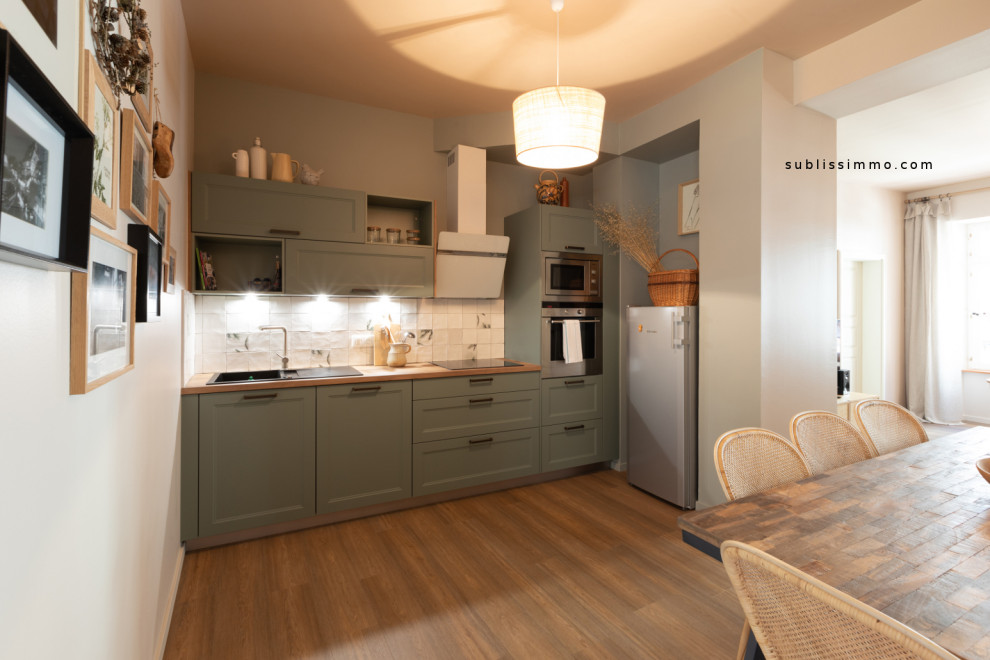 Inspiration for a small traditional single-wall open plan kitchen in Strasbourg with an undermount sink, beaded inset cabinets, green cabinets, laminate benchtops, white splashback, ceramic splashback, stainless steel appliances, light hardwood floors, no island, brown floor and brown benchtop.
