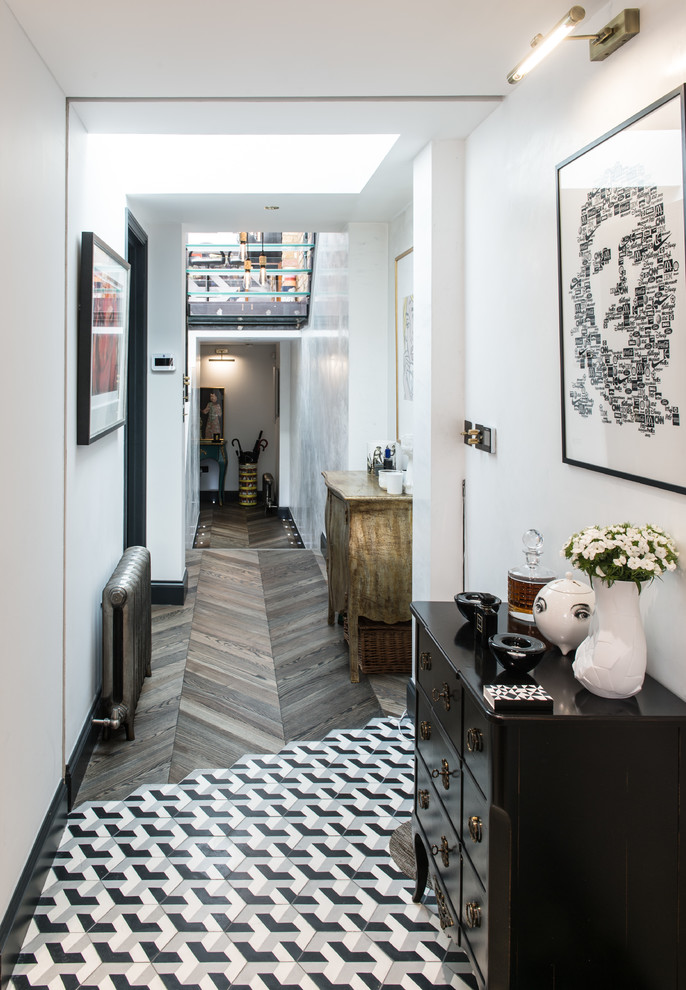 This is an example of a small contemporary hallway in London with white walls, multi-coloured floor and dark hardwood floors.