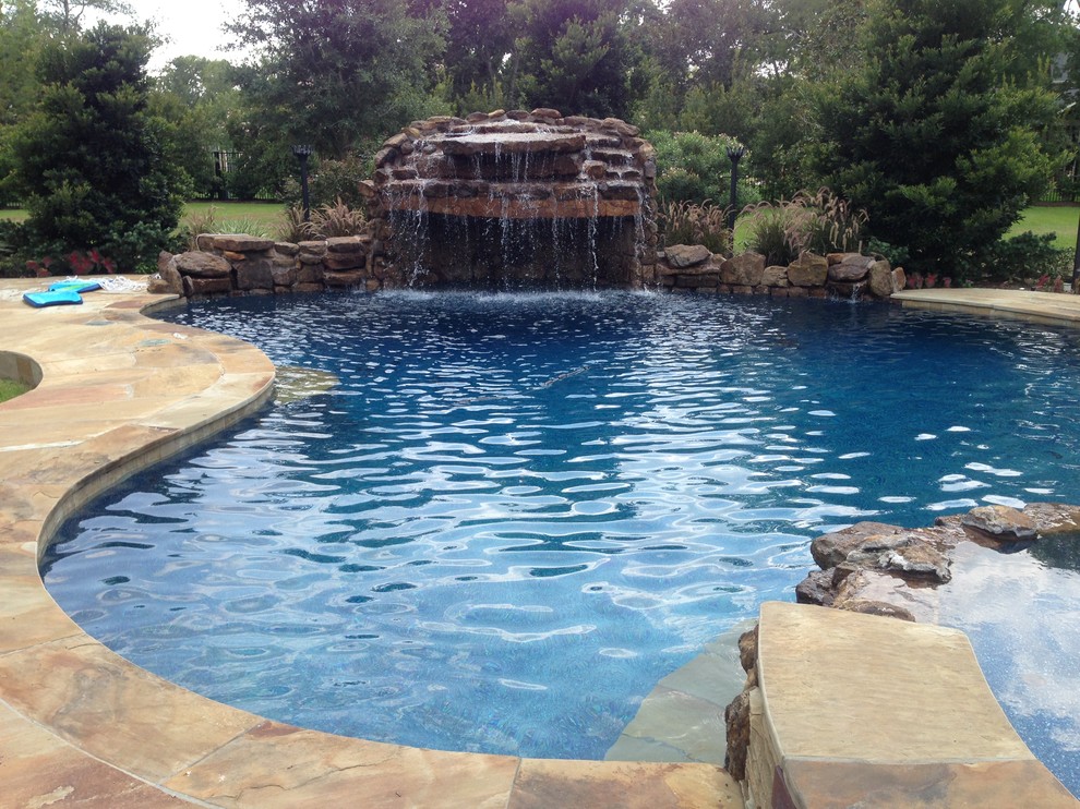 Photo of a mid-sized tropical backyard custom-shaped pool in Houston with a hot tub and concrete pavers.