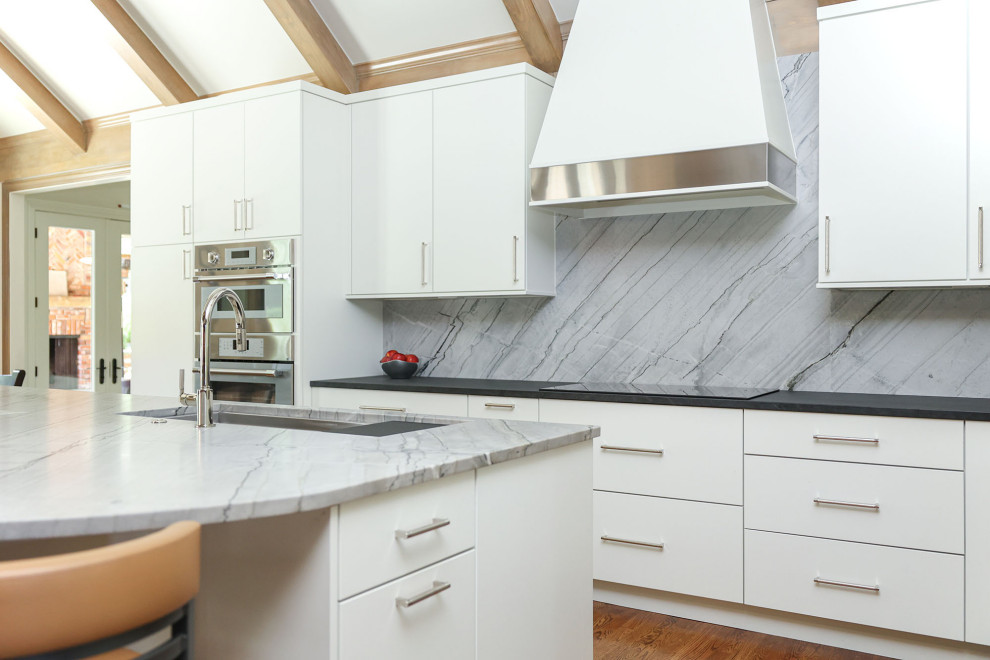 Inspiration for a mid-sized transitional u-shaped medium tone wood floor, brown floor and vaulted ceiling open concept kitchen remodel with an undermount sink, flat-panel cabinets, white cabinets, quartzite countertops, gray backsplash, marble backsplash, stainless steel appliances, an island and gray countertops