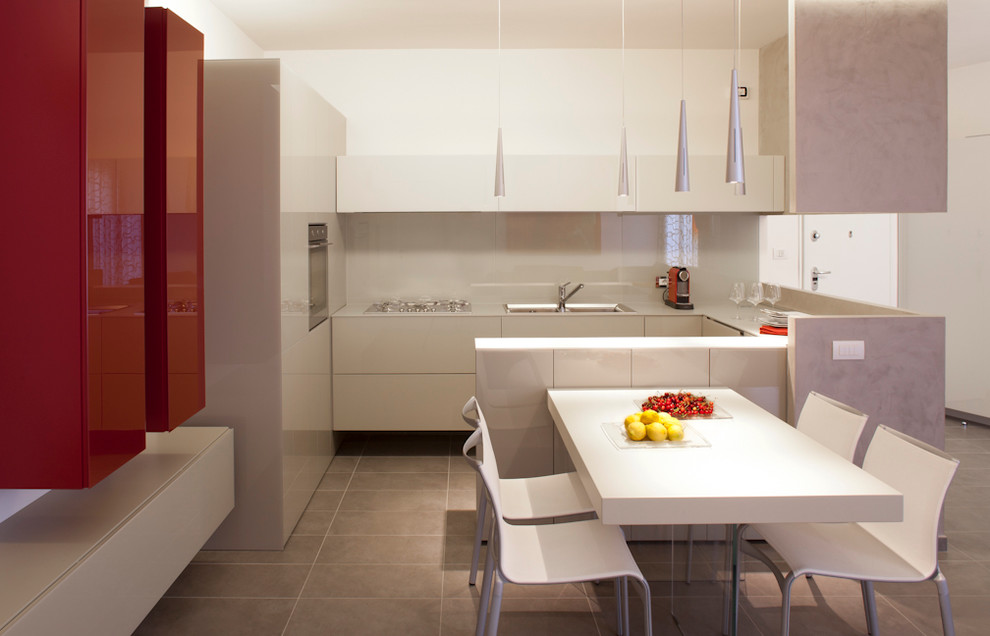 Design ideas for a large contemporary u-shaped open plan kitchen in Catania-Palermo with a drop-in sink, flat-panel cabinets, white cabinets, glass benchtops, white splashback, glass sheet splashback and stainless steel appliances.