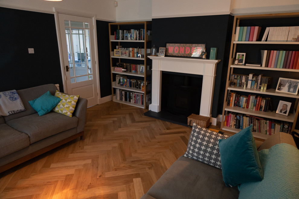 Cette photo montre un salon tendance avec un poêle à bois, un manteau de cheminée en pierre et un sol marron.