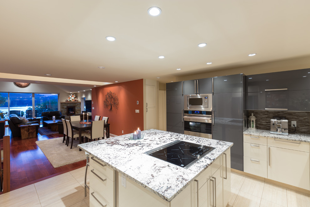 Large contemporary u-shaped open plan kitchen in Vancouver with an undermount sink, flat-panel cabinets, grey cabinets, granite benchtops, multi-coloured splashback, mosaic tile splashback, stainless steel appliances, porcelain floors and with island.