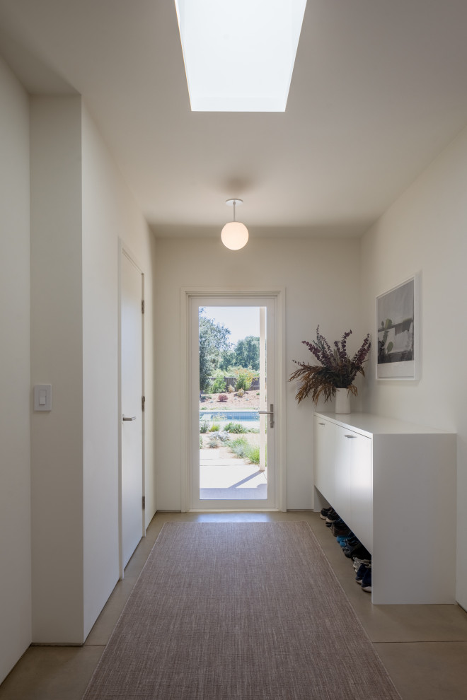 Источник вдохновения для домашнего уюта: большой коридор в стиле модернизм с белыми стенами, бетонным полом, серым полом и сводчатым потолком