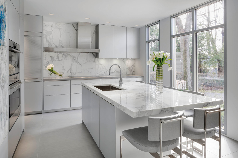 Mid-sized contemporary l-shaped eat-in kitchen in Boston with a single-bowl sink, flat-panel cabinets, white cabinets, marble benchtops, multi-coloured splashback, stone slab splashback, white appliances, with island and ceramic floors.