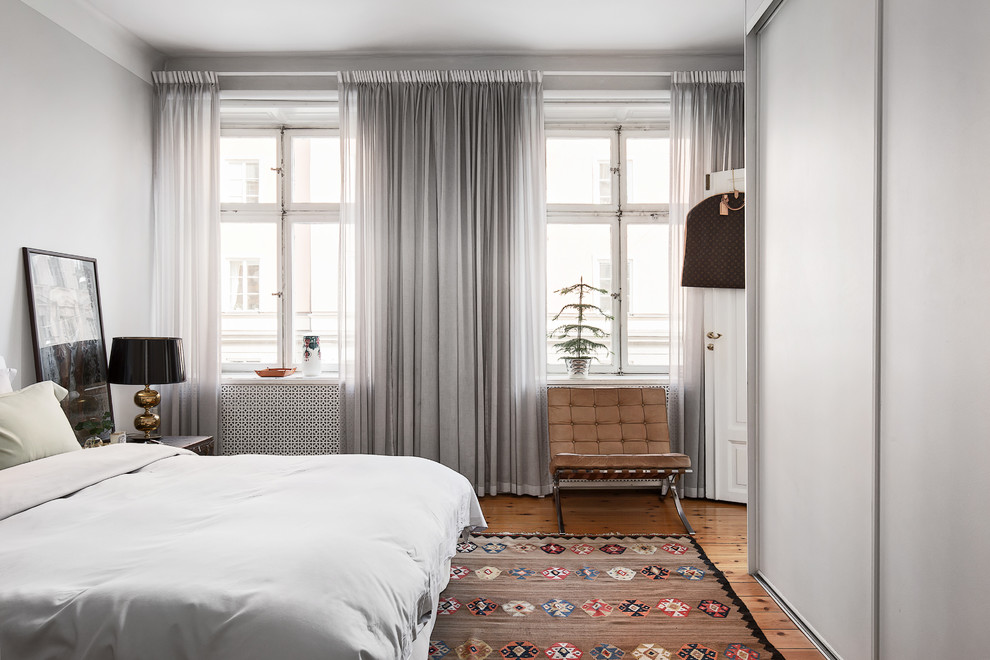 This is an example of a mid-sized scandinavian master bedroom in Stockholm with grey walls, medium hardwood floors and no fireplace.