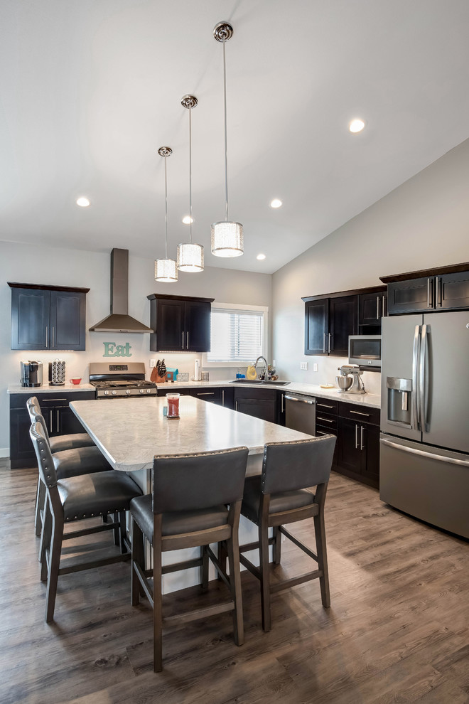 Open concept kitchen - large transitional l-shaped medium tone wood floor open concept kitchen idea with a double-bowl sink, shaker cabinets, dark wood cabinets, quartzite countertops, stainless steel appliances and an island