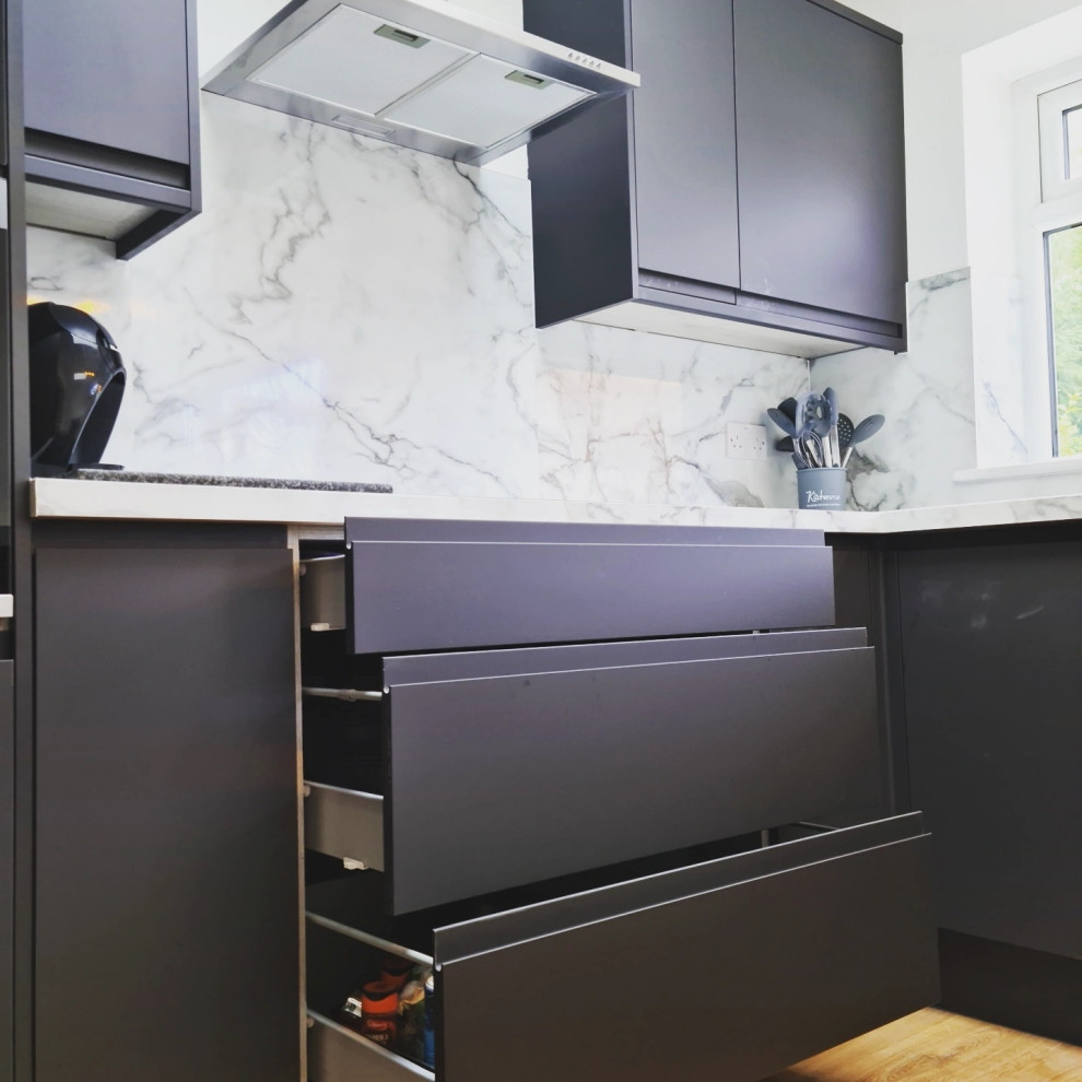 Inredning av ett stort flerfärgad flerfärgat kök, med en enkel diskho, släta luckor, svarta skåp, laminatbänkskiva, integrerade vitvaror, laminatgolv och en halv köksö