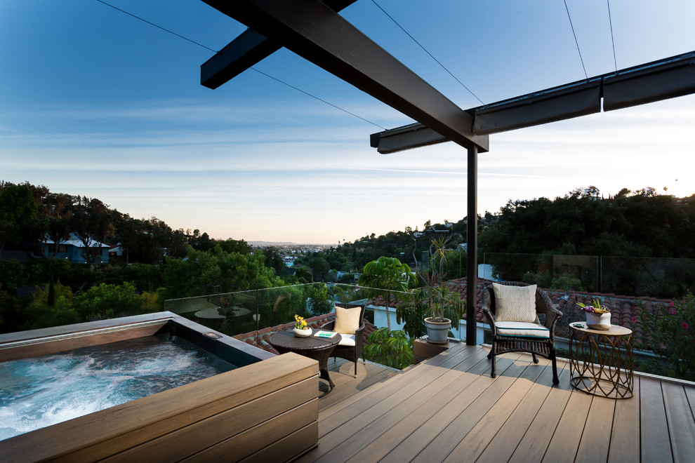 This is an example of a mid-sized mediterranean balcony in Los Angeles with a pergola and glass railing.