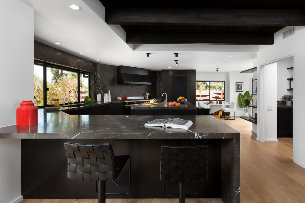 Design ideas for a large midcentury u-shaped open plan kitchen in Orange County with a double-bowl sink, shaker cabinets, black cabinets, marble benchtops, black splashback, marble splashback, panelled appliances, light hardwood floors, with island and beige floor.