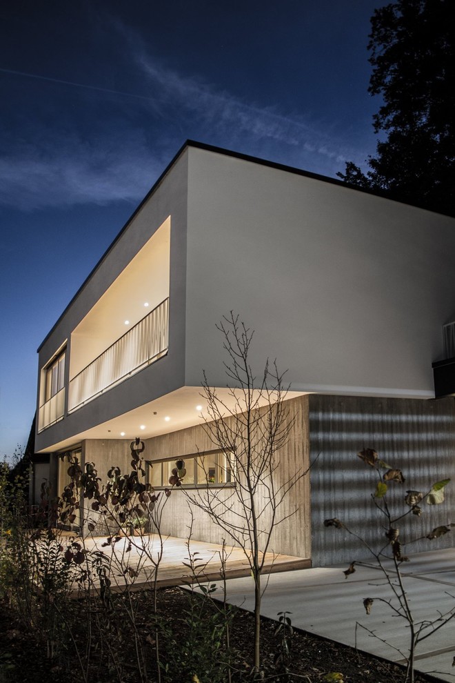 Mid-sized contemporary two-storey concrete grey house exterior in Munich with a flat roof and a green roof.