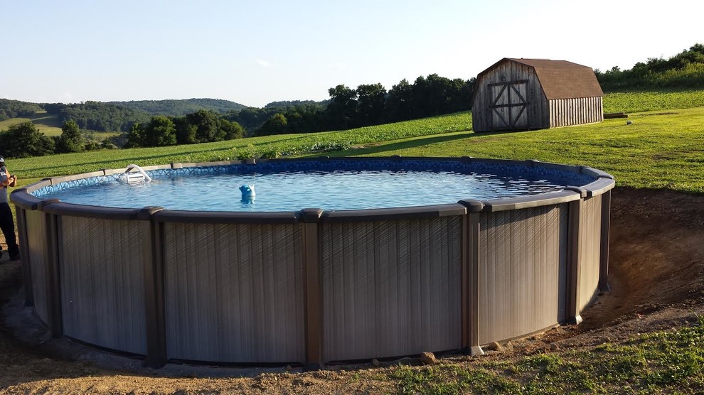 This is an example of a small country backyard round aboveground pool in Other with gravel.