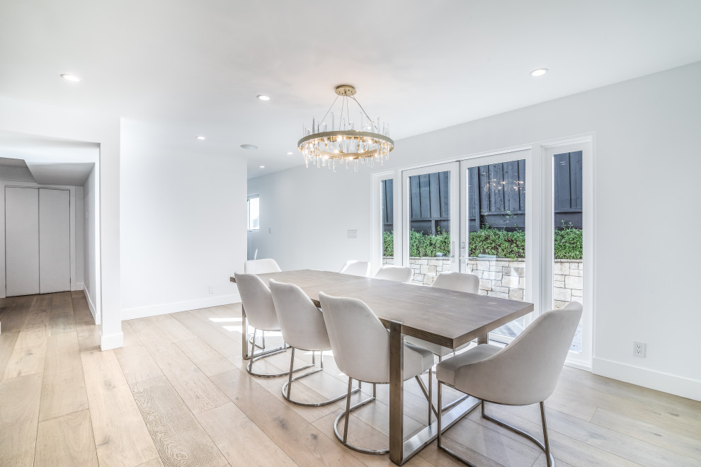 This is an example of a large modern kitchen/dining room in San Francisco with white walls, light hardwood flooring and white floors.