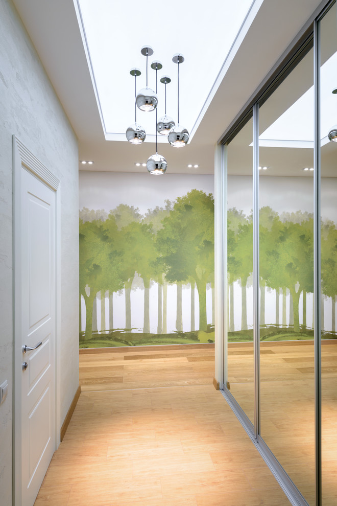 Inspiration for a mid-sized contemporary hallway in Novosibirsk with light hardwood floors and white walls.