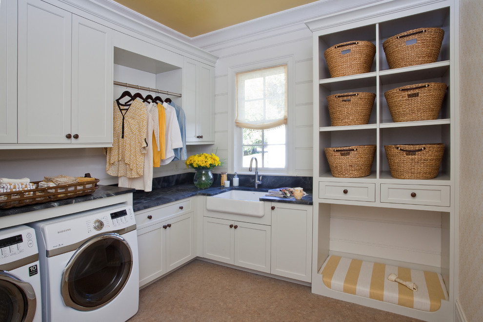 Inspiration for a transitional l-shaped dedicated laundry room in Other with a farmhouse sink, shaker cabinets, white cabinets, a side-by-side washer and dryer, cork floors and black benchtop.