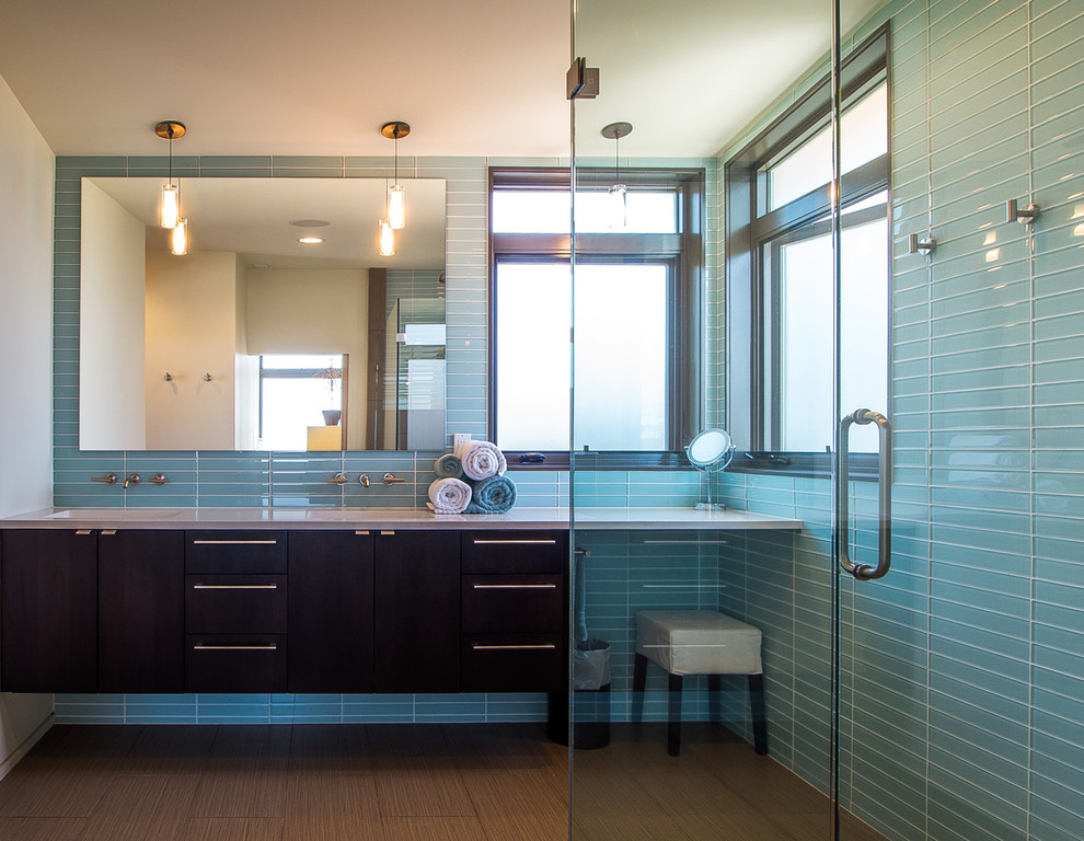 Mid-sized contemporary master bathroom in Seattle with flat-panel cabinets, black cabinets, a corner shower, blue tile, glass tile, blue walls, bamboo floors, an integrated sink, brown floor, a hinged shower door and white benchtops.