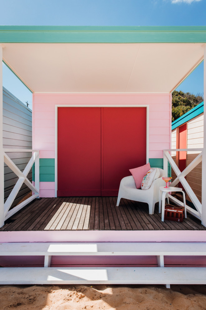 This is an example of a small beach style one-storey pink exterior in Other with wood siding.