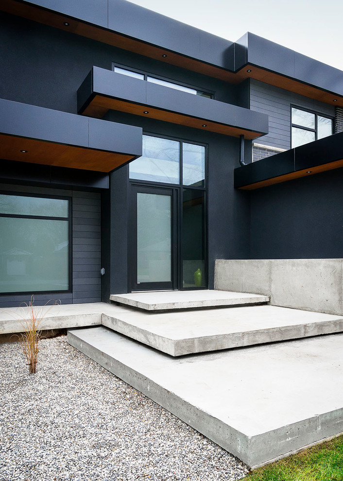 Design ideas for a large modern two-storey stucco black exterior in Toronto with a flat roof.
