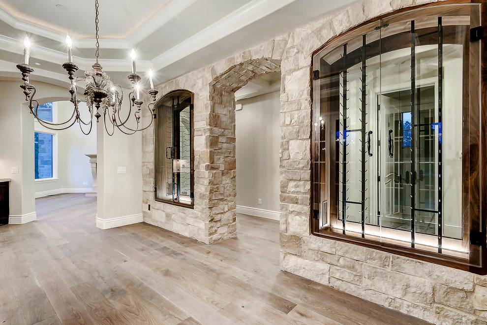 Design ideas for a mid-sized traditional wine cellar in Denver with light hardwood floors, display racks and brown floor.