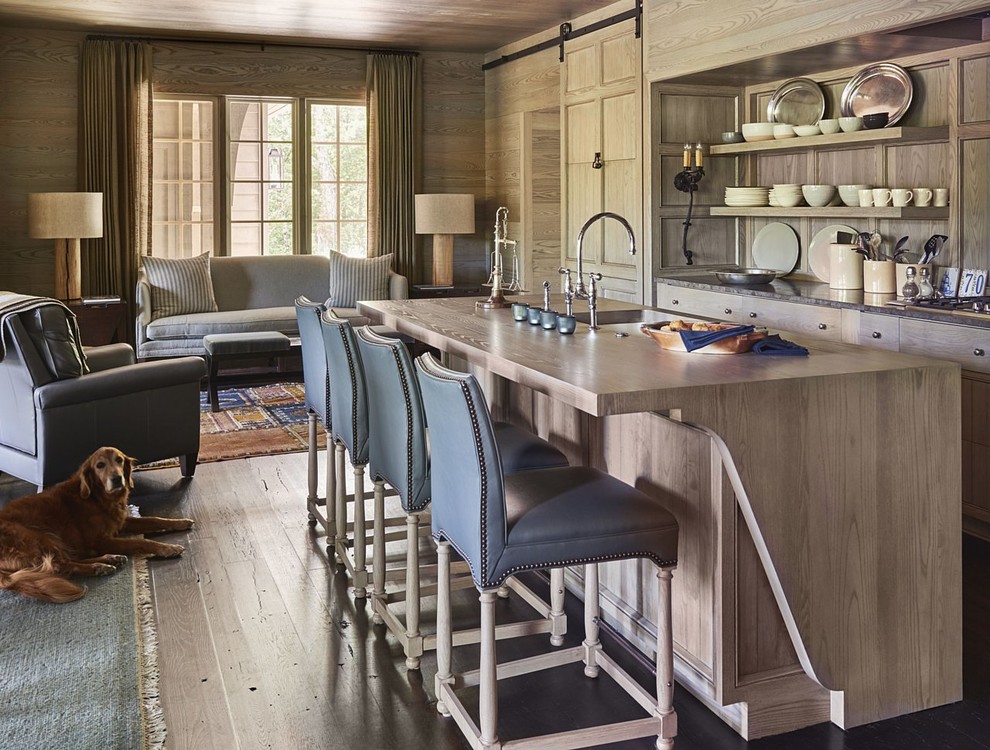 This is an example of a mid-sized country single-wall open plan kitchen in Charlotte with an undermount sink, recessed-panel cabinets, grey cabinets, granite benchtops, panelled appliances, light hardwood floors and with island.