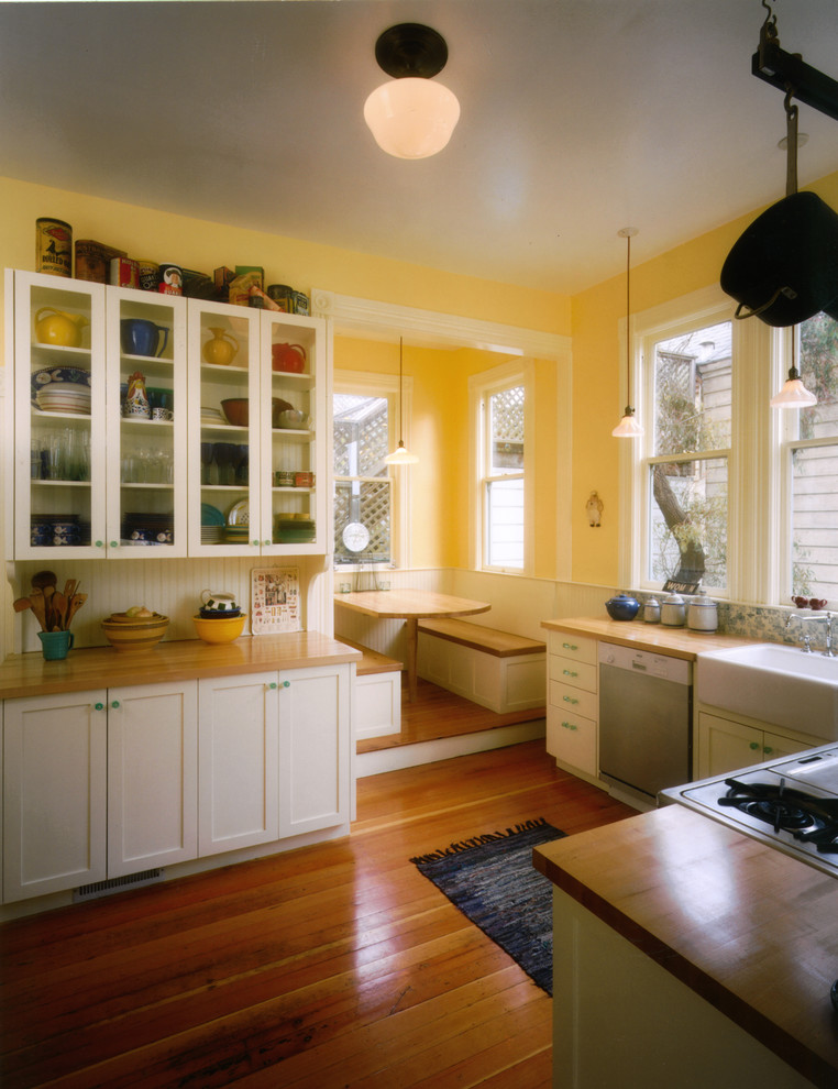 This is an example of a contemporary kitchen in San Francisco with a farmhouse sink, shaker cabinets, white cabinets, wood benchtops and medium hardwood floors.