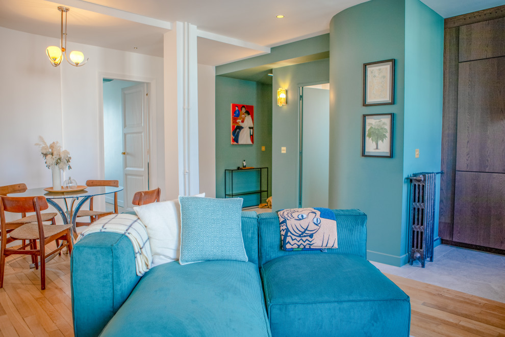 Example of a mid-sized transitional open concept medium tone wood floor, gray floor and tray ceiling living room design in Paris with a bar, green walls and no tv