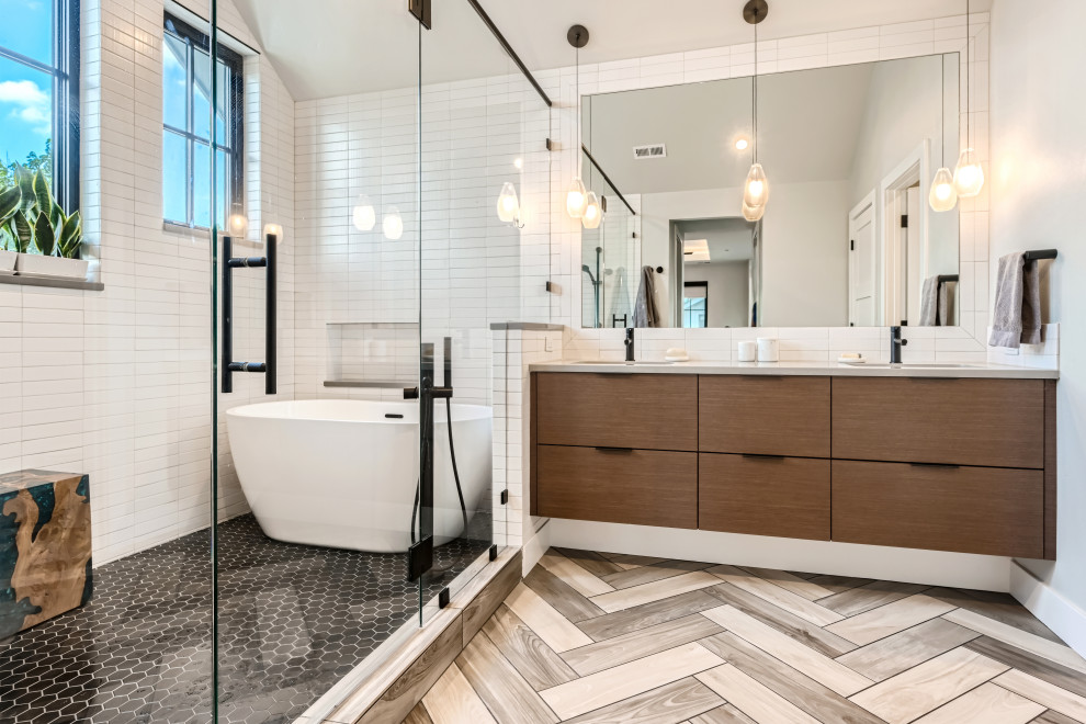 Design ideas for a large contemporary ensuite wet room bathroom in Denver with flat-panel cabinets, dark wood cabinets, a freestanding bath, white tiles, ceramic tiles, white walls, porcelain flooring, a submerged sink, engineered stone worktops, beige floors, a hinged door, white worktops, double sinks, a floating vanity unit and a vaulted ceiling.