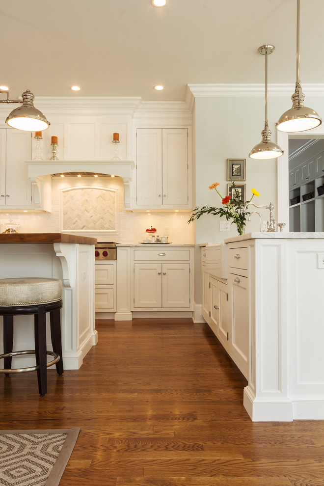 Large transitional medium tone wood floor kitchen pantry photo in New York with white cabinets, marble countertops, white backsplash, porcelain backsplash, stainless steel appliances, two islands and a farmhouse sink