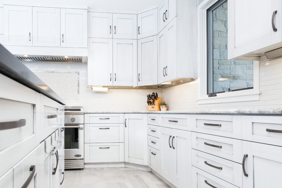 Inspiration for a large transitional l-shaped porcelain tile eat-in kitchen remodel in Austin with a single-bowl sink, shaker cabinets, gray cabinets, soapstone countertops, white backsplash, ceramic backsplash, stainless steel appliances and an island