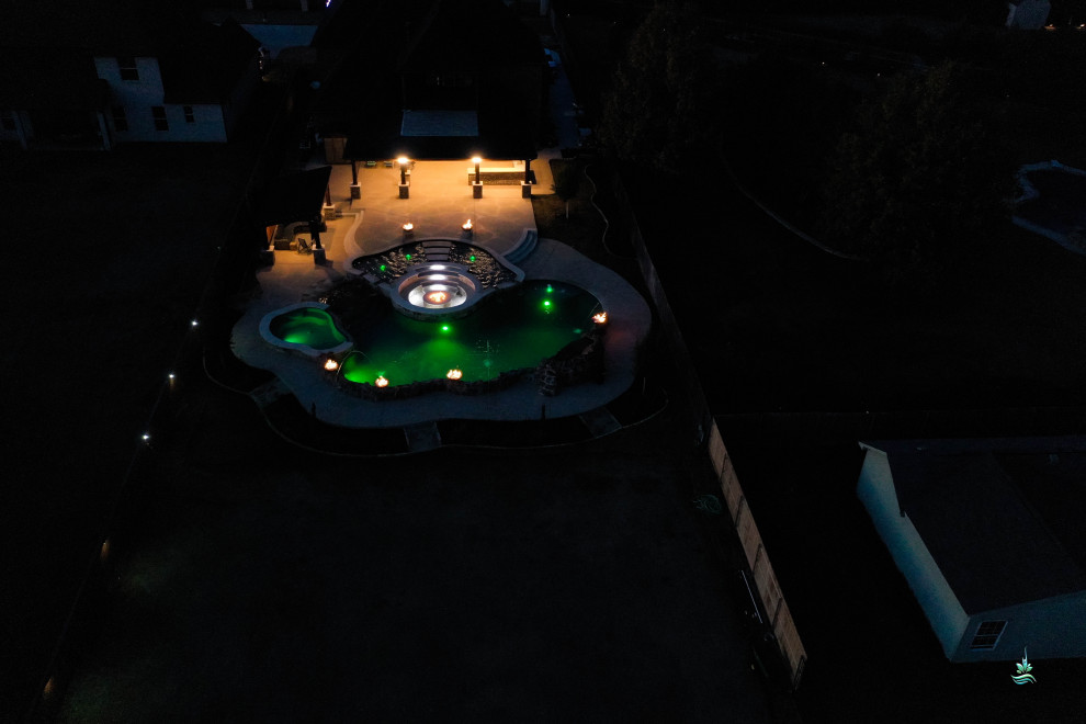Foto di un'ampia piscina naturale rustica personalizzata dietro casa con paesaggistica bordo piscina e pavimentazioni in cemento