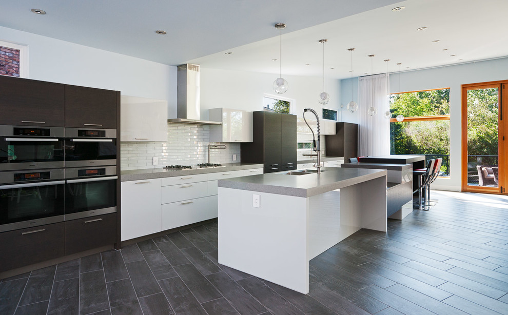 Inspiration for a contemporary galley open plan kitchen in Calgary with a drop-in sink, flat-panel cabinets, white cabinets, quartz benchtops, white splashback, subway tile splashback and panelled appliances.