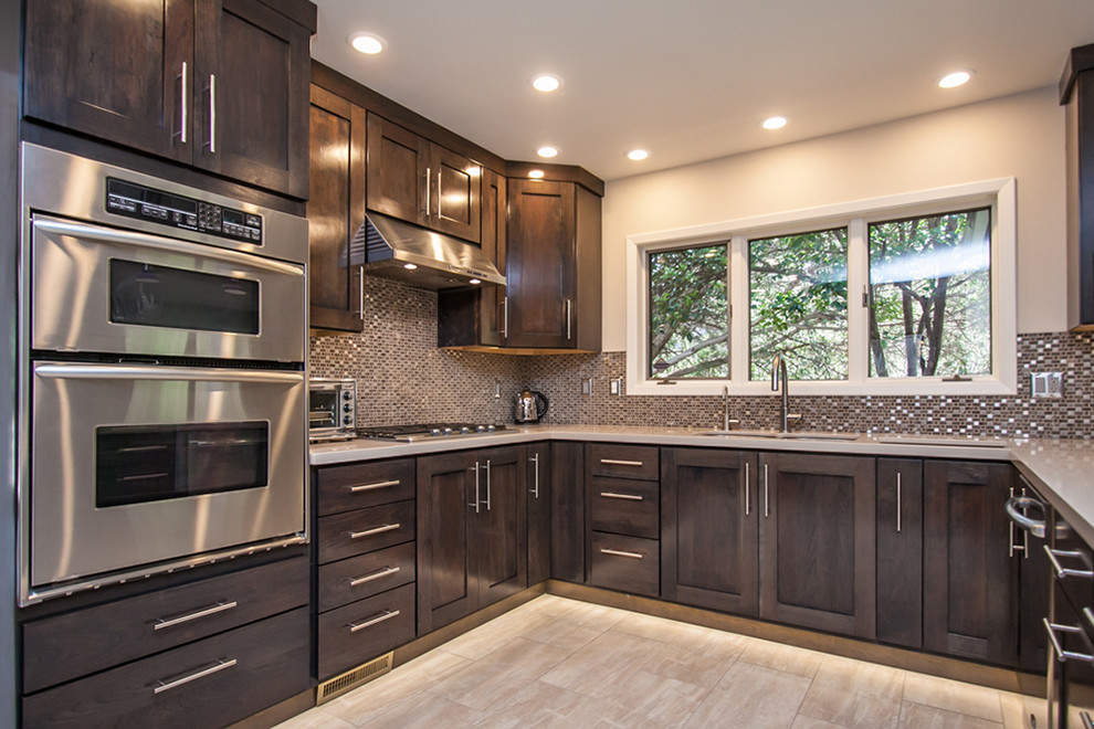 Inspiration for a mid-sized transitional u-shaped light wood floor and beige floor eat-in kitchen remodel in Phoenix with an undermount sink, shaker cabinets, granite countertops, multicolored backsplash, stainless steel appliances, an island, dark wood cabinets and mosaic tile backsplash